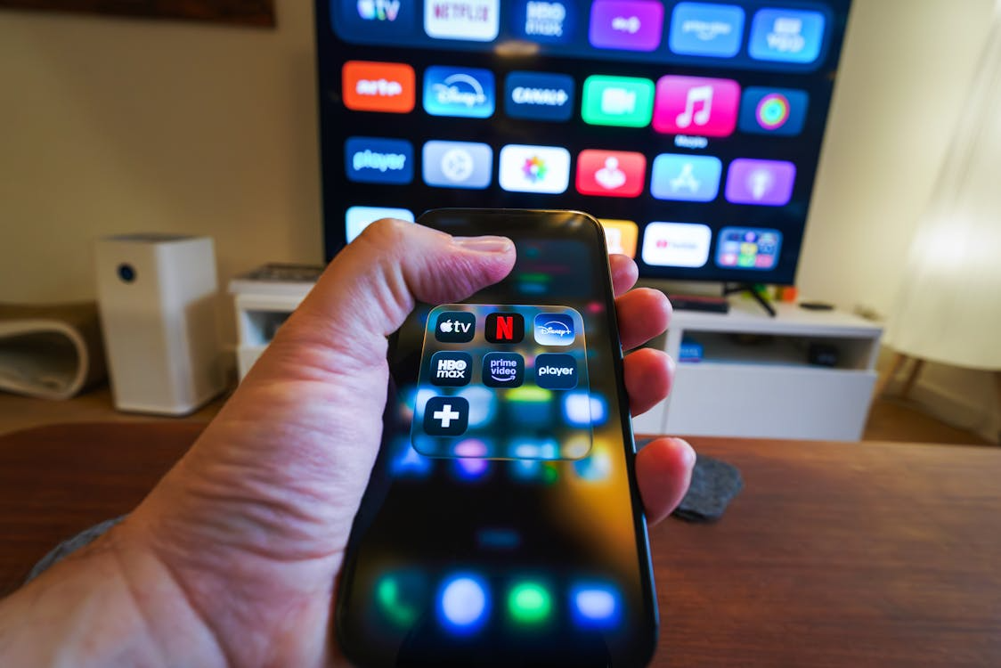 Comparing Netflix vs Hulu vs Disney Plus on a phone and TV before choosing a streaming service.