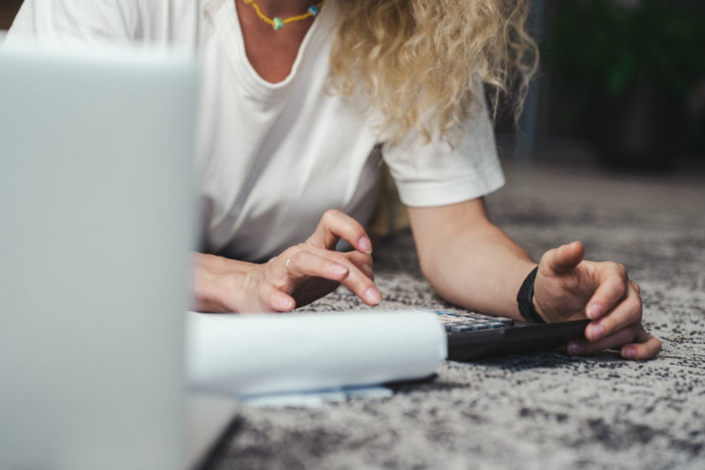 Woman using a calculator and paperwork to complete a monthly bill audit checklist.